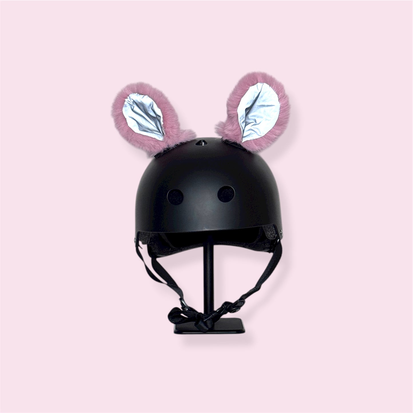 Black helmet with pink bunny ears on a light pink background